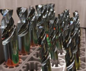 Batch of carbide tools with polished flutes standing in a production tray.