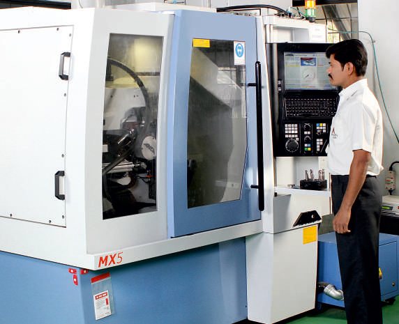 Operator working at a CNC tool and cutter grinding machine on the shop floor.
