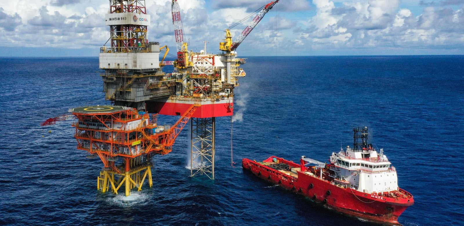 Offshore oil and gas production platform with a supply vessel alongside.